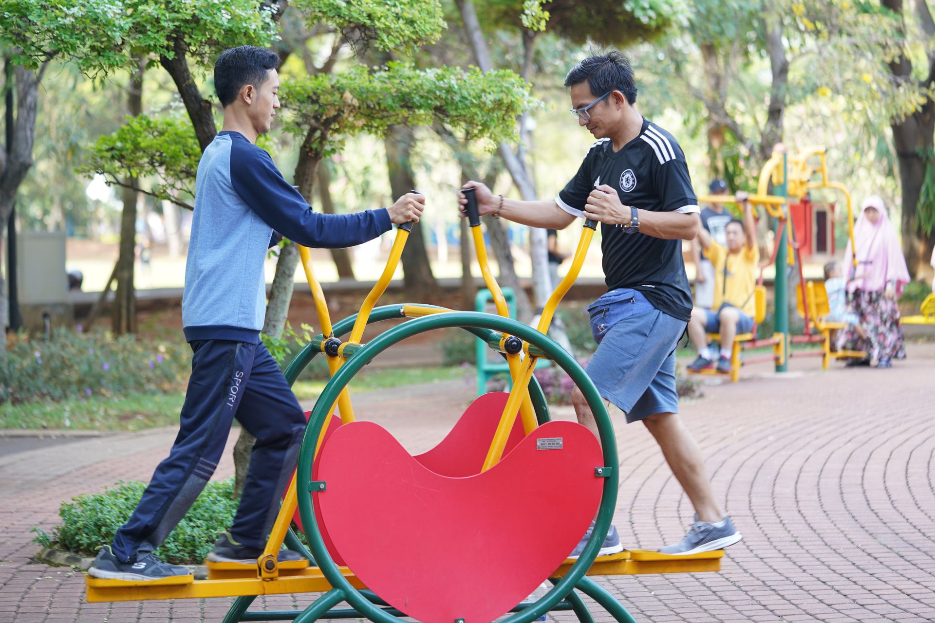 People using outdoor fitness equipment in a community park