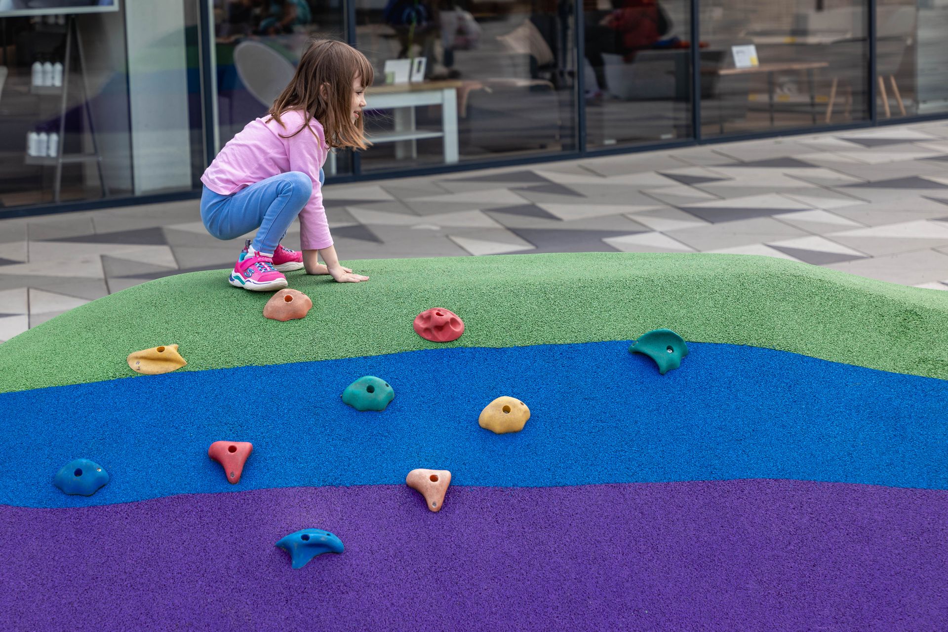 Child climbing colorful poured rubber mounds