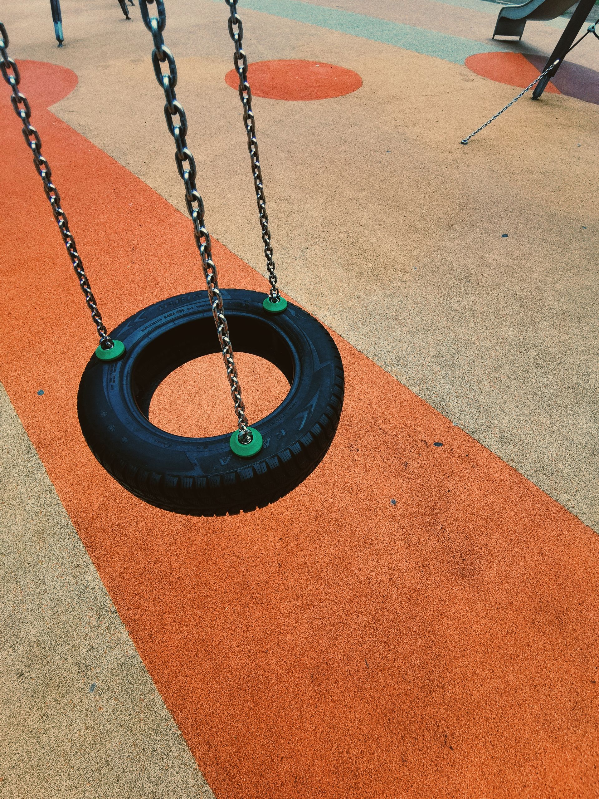 Tire swing over orange and blue rubber safety surfacing
